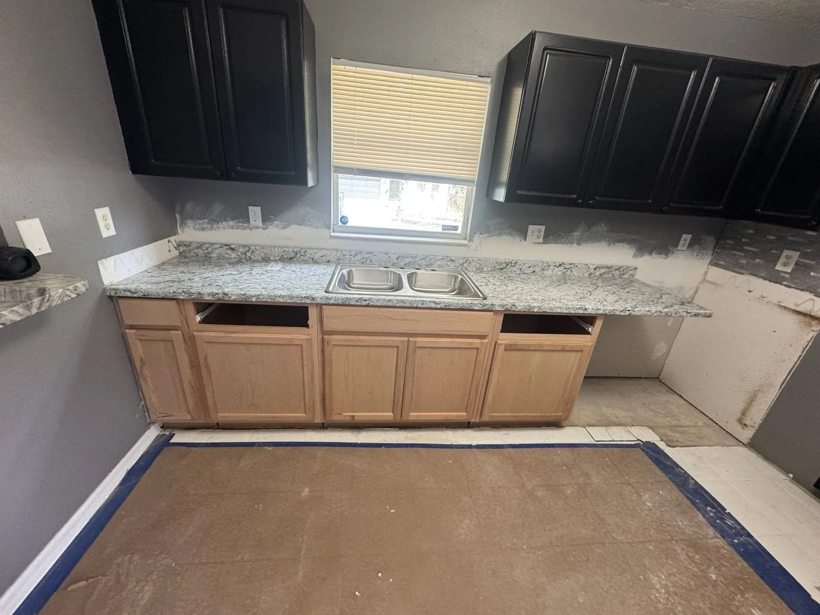 New base cabinets installed in the kitchen mid-rehabilitation, walls prepped and countertops not yet set
