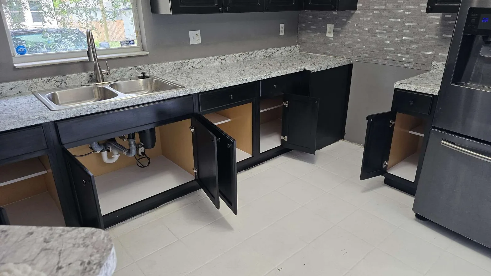The rebuilt under-sink cabinet with clean plumbing and fresh shelf liners after the rehabilitation